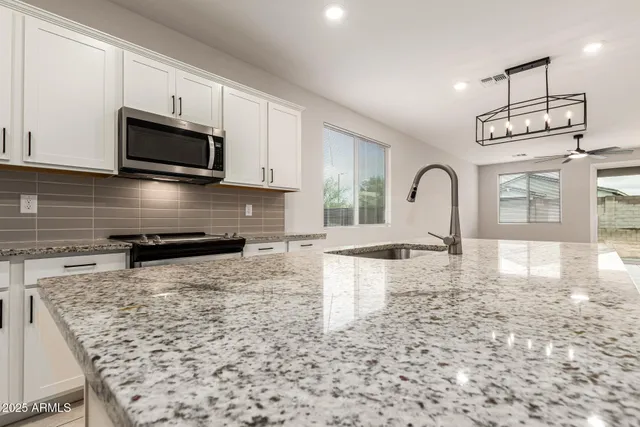 a kitchen with stainless steel appliances granite countertop a stove a sink and a microwave