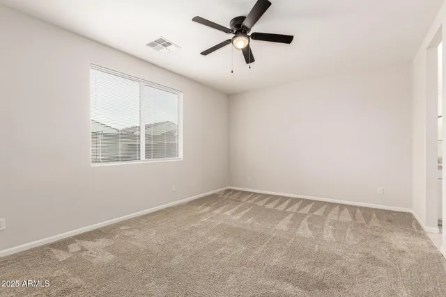 an empty room with windows and ceiling fan