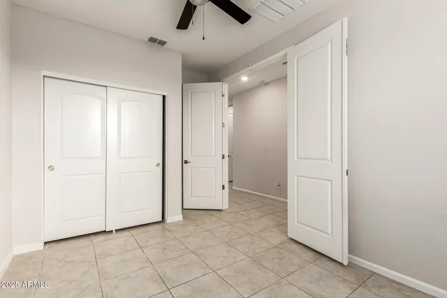 an empty room with closet and a chandelier fan
