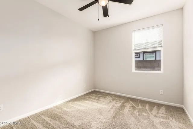 an empty room with a window and a ceiling fan