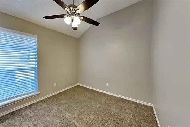 an empty room with a window and a fan