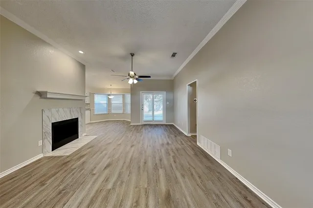 a view of an empty room with wooden floor fireplace and a window