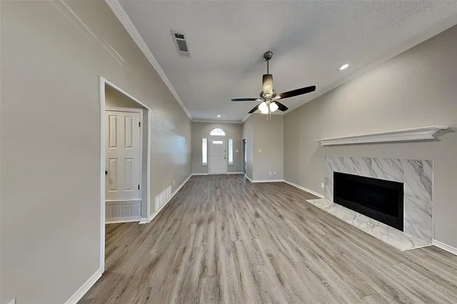 a view of an empty room with wooden floor fireplace and a window