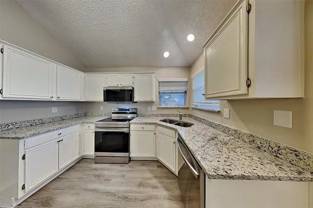 a kitchen with granite countertop a sink stove and cabinets
