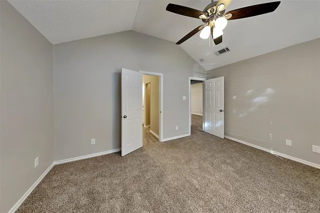 en empty room with chandelier fan and windows