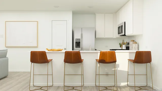 a kitchen with granite countertop a table chairs and white cabinets