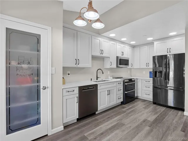 a kitchen with stainless steel appliances granite countertop a refrigerator a stove a sink and white cabinets