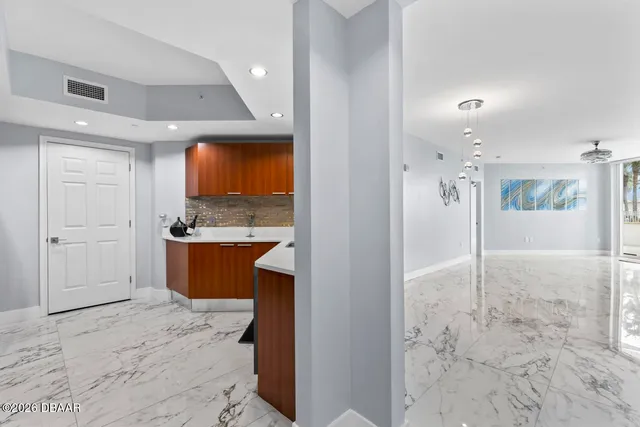 a view of kitchen with kitchen island granite countertop a refrigerator and a sink