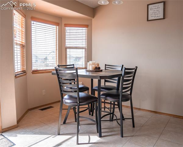 8298 Bohleen Road Peyton, CO 80831 - Photo 14 of 28 Dining area adjacent to the kitchen with bay window overlooking the large backyard and ceramic tile floor.