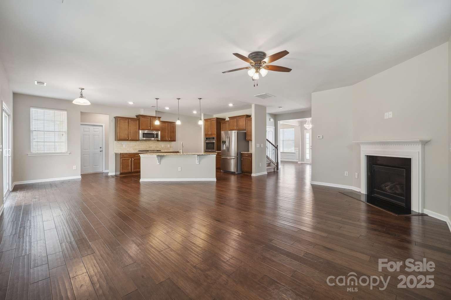 128 Yellowbell Road Mooresville, NC 28117 - Photo 8 of 19 a view of a kitchen and an empty room with wooden floor and a kitchen