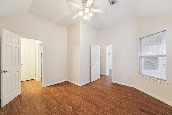 an empty room with wooden floor closet and windows