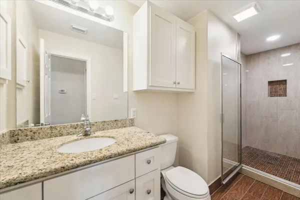 a bathroom with a granite countertop sink toilet and shower