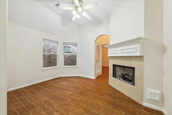 a view of an empty room with chandelier fan and fire place