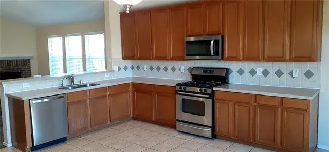 a kitchen with stainless steel appliances granite countertop a stove a sink and a microwave