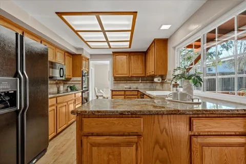 a kitchen with stainless steel appliances granite countertop a refrigerator a sink a stove and cabinets