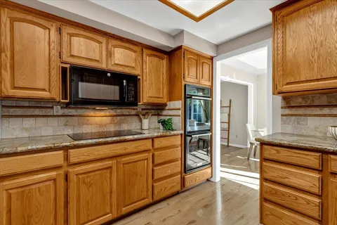 a kitchen with stainless steel appliances granite countertop wooden cabinets and a stove top oven
