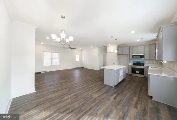 a view of a kitchen with kitchen island a counter top space a sink wooden floor and a large window