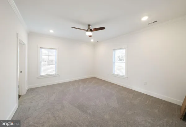 en empty room with windows and ceiling fan