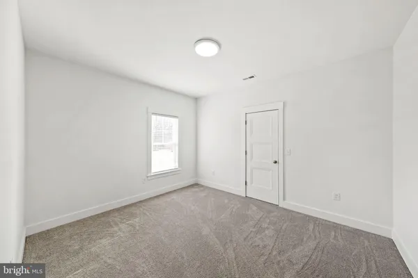 a view of an empty room with a window and closet area