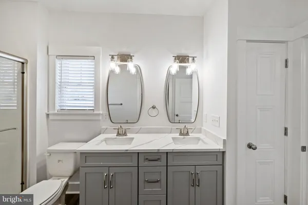 a bathroom with 2 sink toilet and a mirror