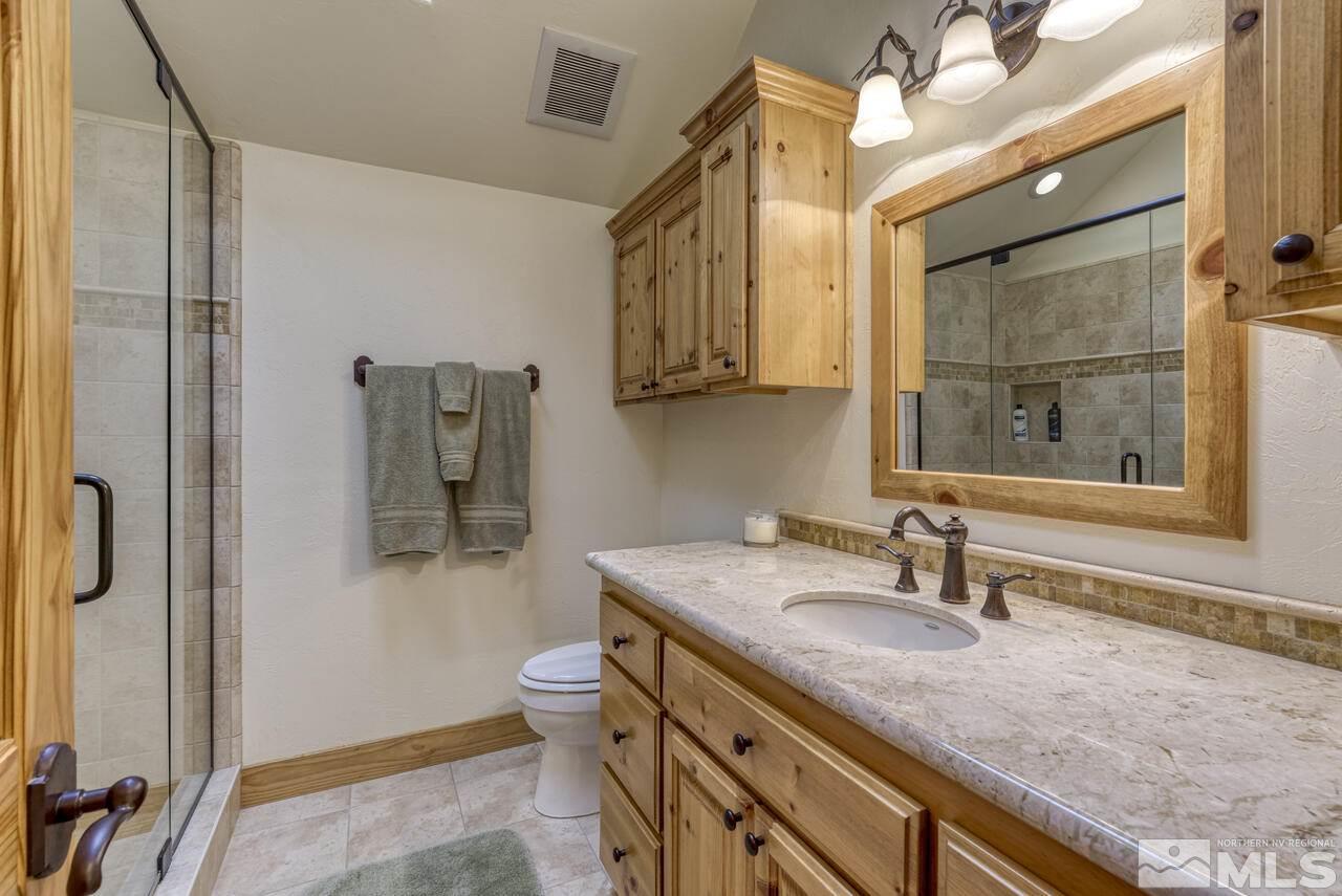 40 Grannie Lane Wellington, NV 89444 - Photo 27 of 40 a bathroom with a granite countertop sink a mirror a vanity and shower