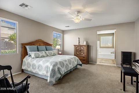 a bedroom with a bed a computer on desk and a dresser