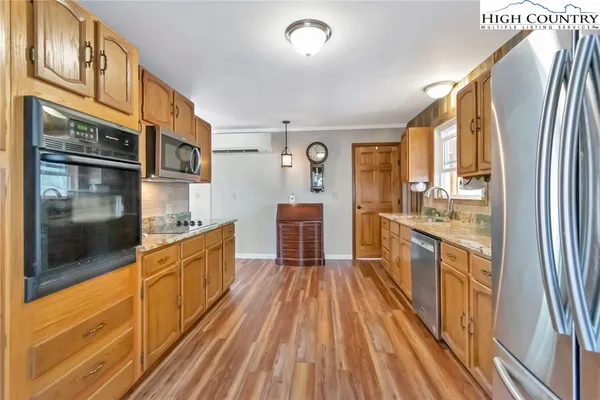 a large kitchen with stainless steel appliances a large counter top a stove and a refrigerator