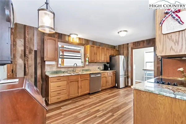 a kitchen with stainless steel appliances granite countertop a refrigerator a sink dishwasher a stove and a dining table with wooden floor