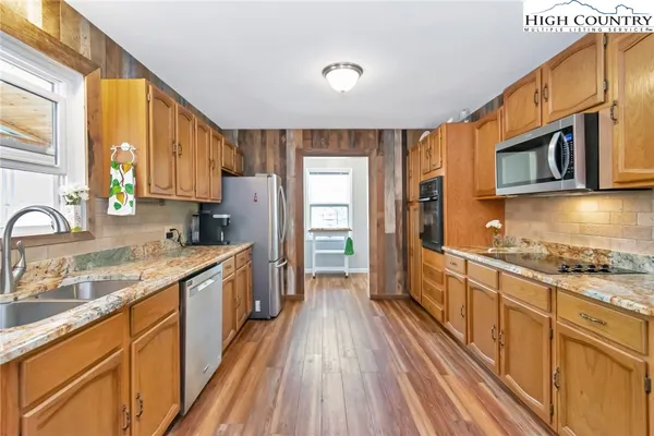 a large kitchen with stainless steel appliances granite countertop a lot of counter space and wooden floors