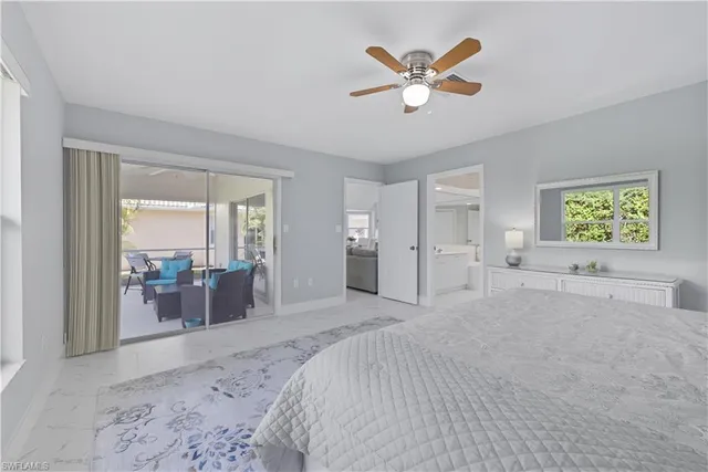 a spacious bedroom with a large bed a chandelier and windows