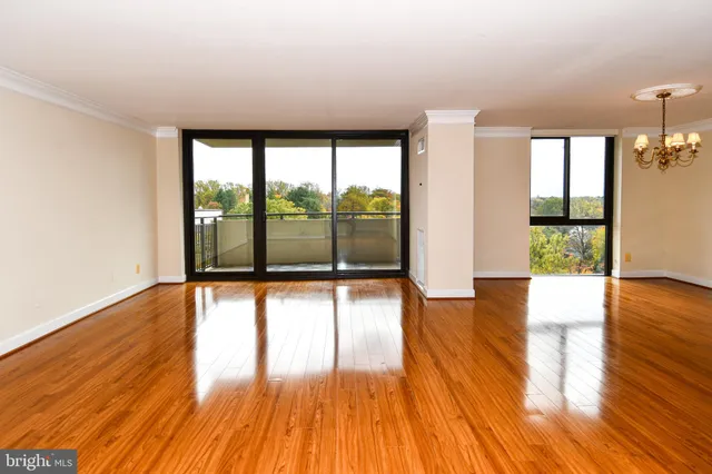 a view of empty room with wooden floor and floor to ceiling window