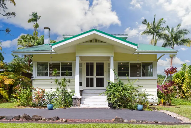 a front view of a house with a yard and potted plants
