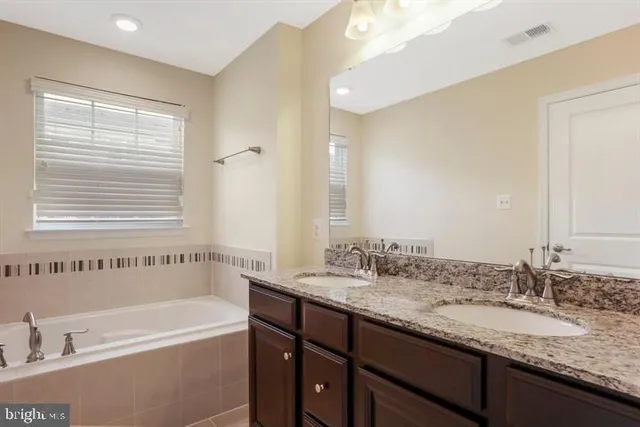 a bathroom with a granite countertop sink and a bathtub