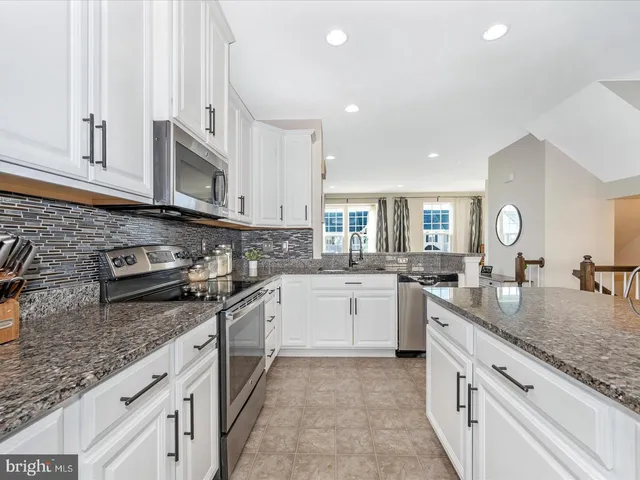 a large kitchen with stainless steel appliances granite countertop a lot of counter space and a sink