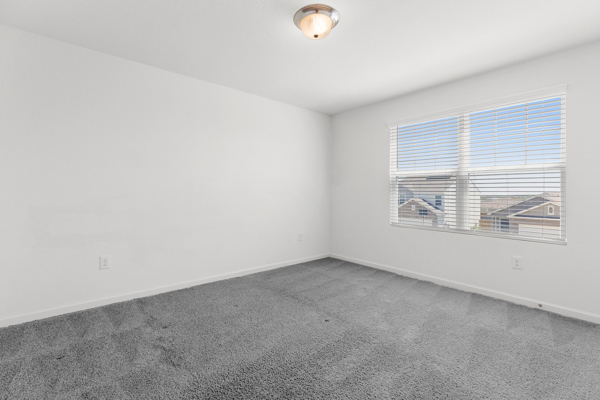 409 Line Of Fire Way Jarrell, TX 76537 - Photo 26 of 30 Room featuring neutral wall paint, gray carpet flooring, single window with horizontal blinds, ceiling-mounted light fixture, white trim, and open wall space.