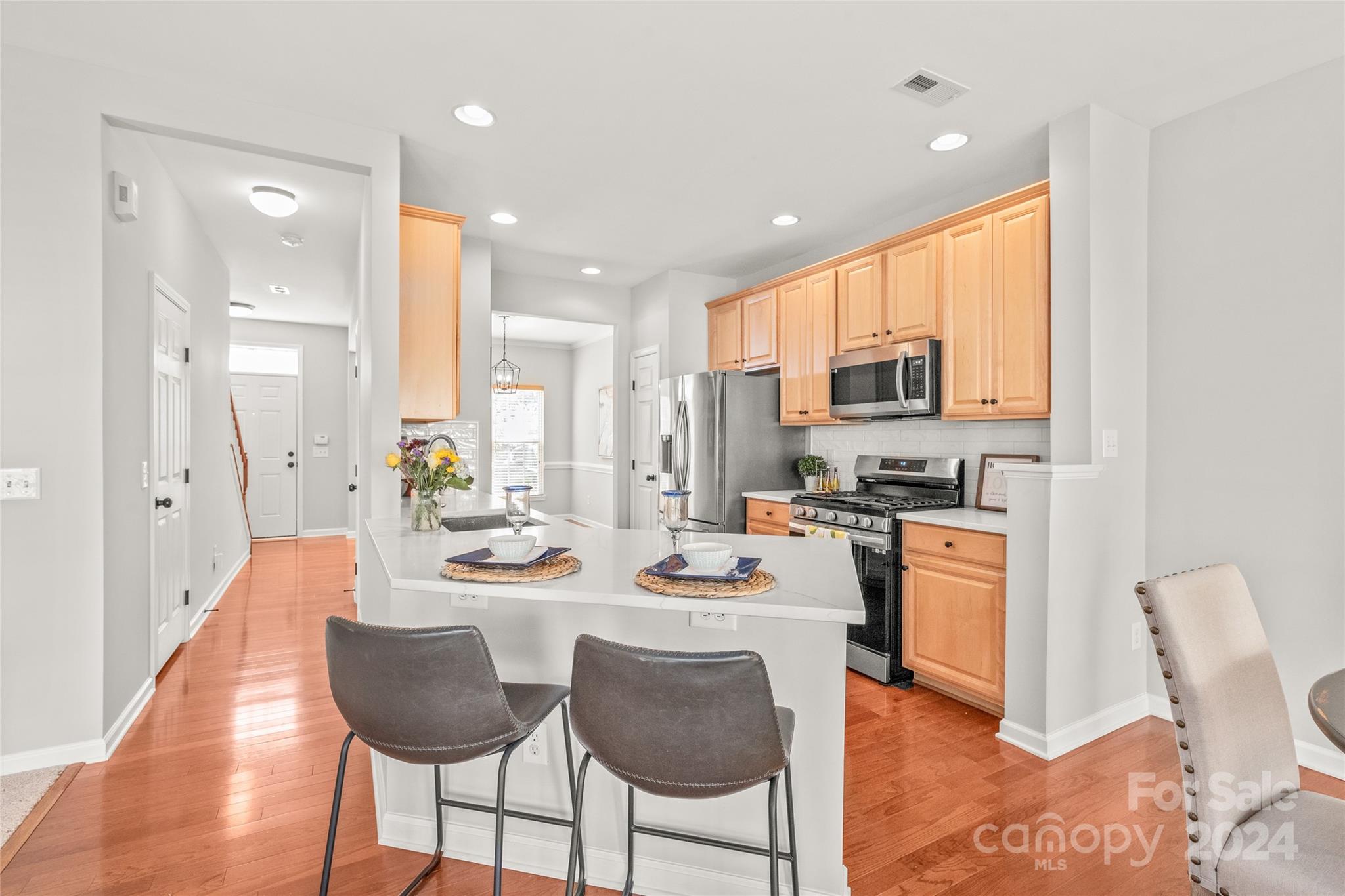 205 Snead Road Fort Mill, SC 29715 - Photo 8 of 33 a kitchen with stainless steel appliances kitchen island granite countertop a stove a sink a refrigerator a dining table and chairs