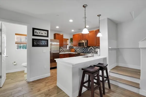 a kitchen with stainless steel appliances kitchen island granite countertop a refrigerator a stove and a wooden floor