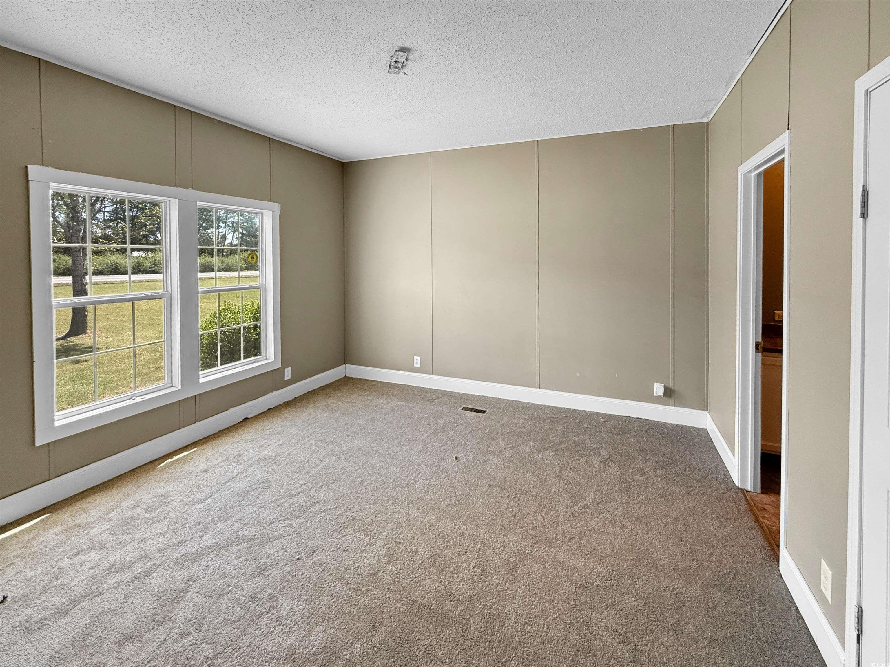 111 Morrisville Road Andrews, SC 29510 - Photo 17 of 28 Empty room featuring a decorative wall, baseboards, carpet flooring, and a textured ceiling