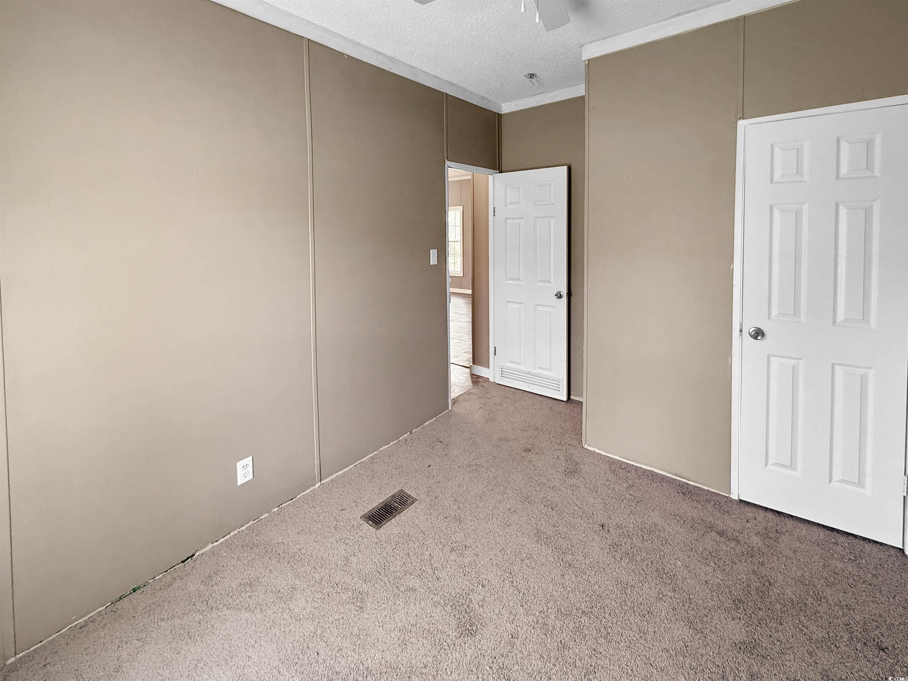 111 Morrisville Road Andrews, SC 29510 - Photo 18 of 28 Unfurnished bedroom featuring a textured ceiling, a ceiling fan, crown molding, carpet floors, and visible vents