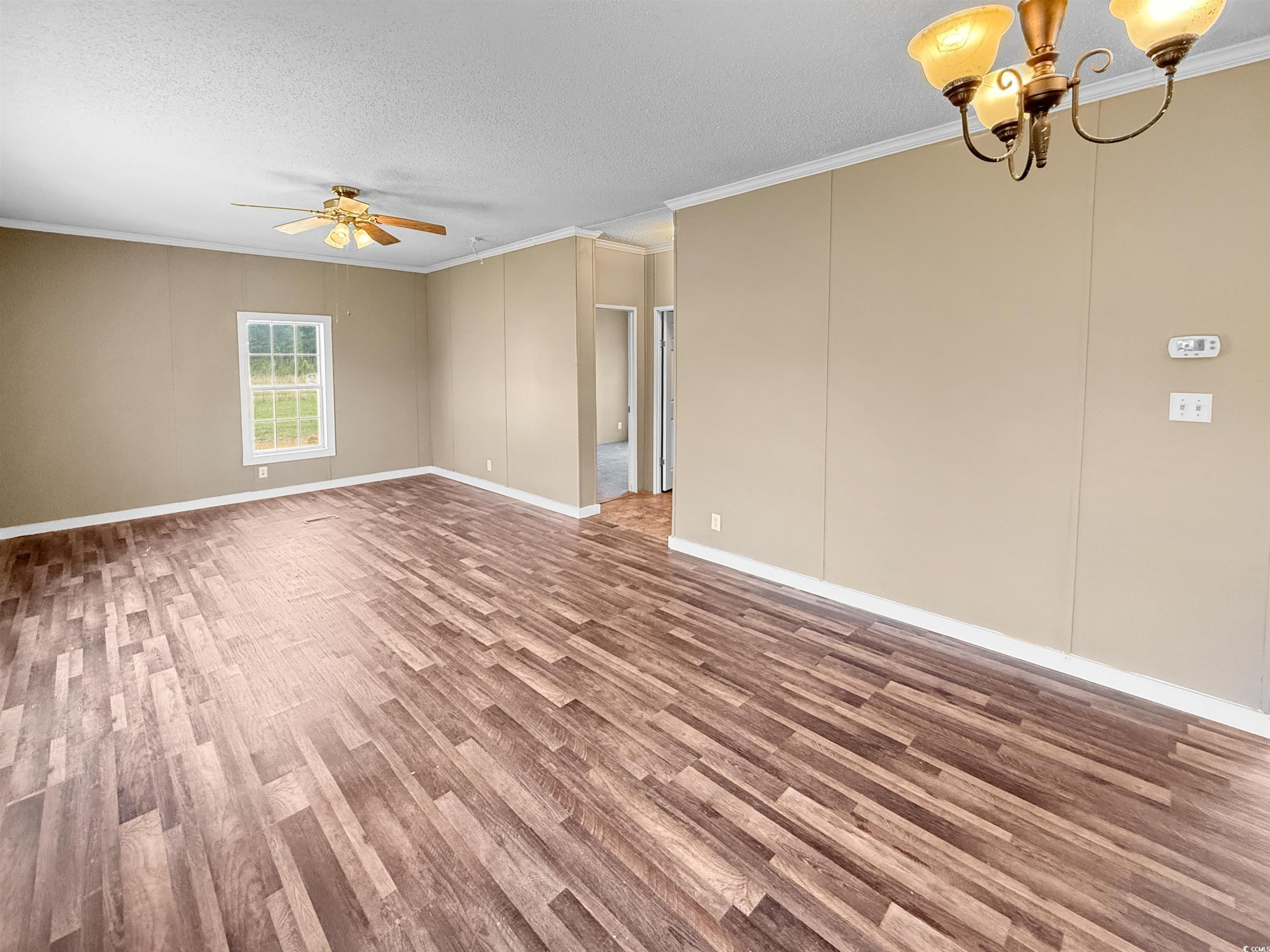 111 Morrisville Road Andrews, SC 29510 - Photo 10 of 28 Unfurnished room featuring baseboards, ornamental molding, a textured ceiling, ceiling fan with notable chandelier, and wood finished floors