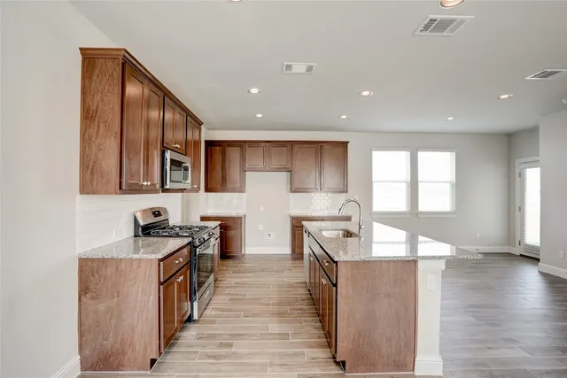 a kitchen with granite countertop a stove top oven a sink a counter space and cabinets