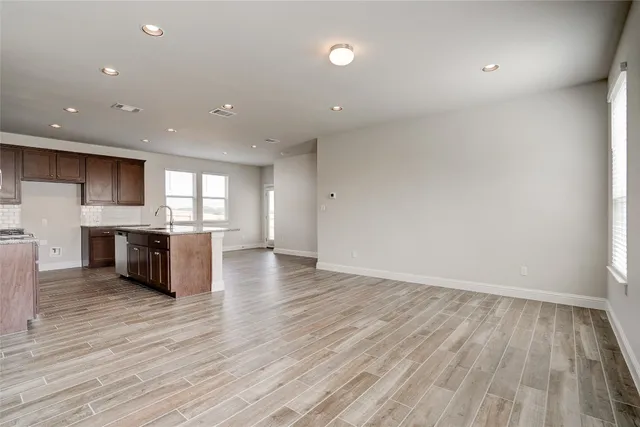 a large kitchen with stainless steel appliances a large counter top a stove and a wooden floors