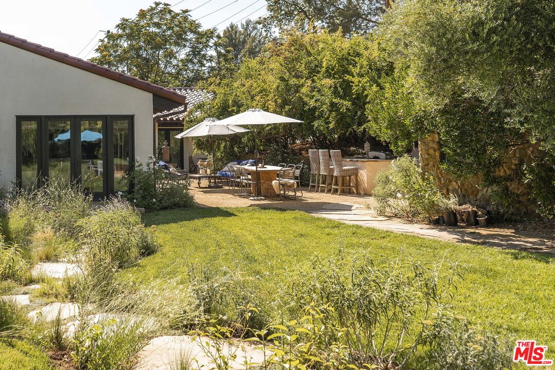 2251 Cold Canyon Road Calabasas, CA 91302 - Photo 40 of 47 a backyard of a house with table and chairs under an umbrella