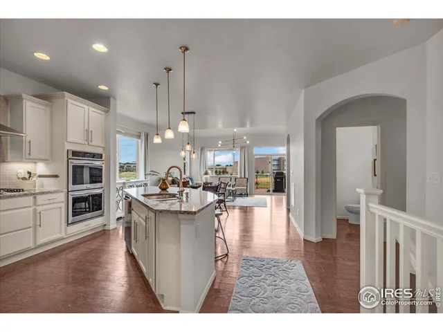 a kitchen with stainless steel appliances granite countertop a refrigerator a stove a sink dishwasher and white cabinets with wooden floor