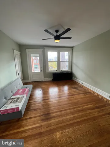 a view of an empty room with window and hardwood floor