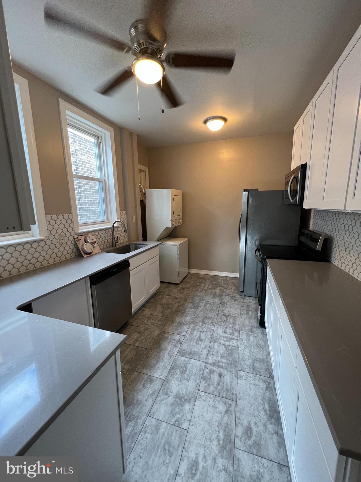 5931 Carpenter Street Philadelphia, PA 19143 - Photo 7 of 15 a kitchen with stainless steel appliances granite countertop a sink a stove and a refrigerator