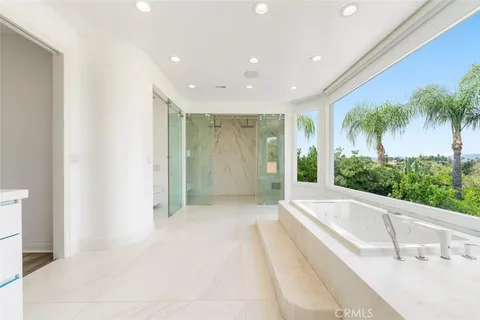 a bathroom with a bathtub a sink a window and a mirror