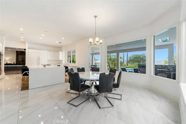 a view of a kitchen with kitchen island a stove a sink a refrigerator and a dining table with wooden floor