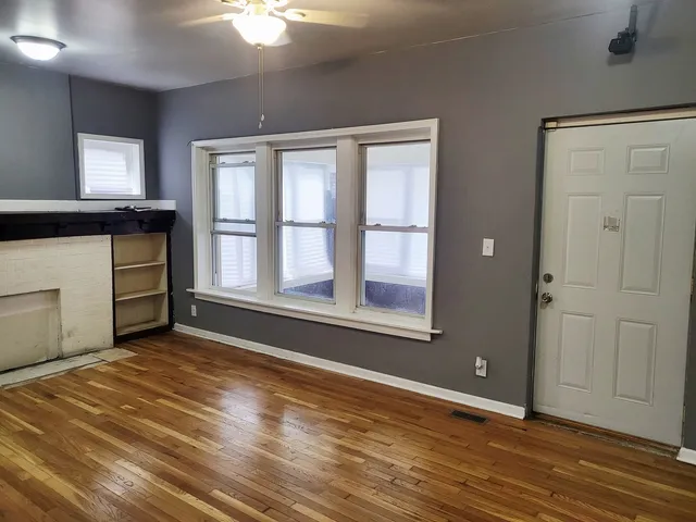 a view of an empty room with window and wooden floor