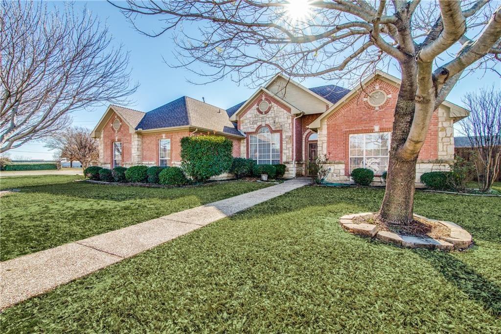 a front view of a house with a yard and large tree